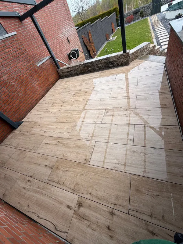 Neu geflieste Terrasse in Holzoptik mit Blick auf Garten und Zaun
