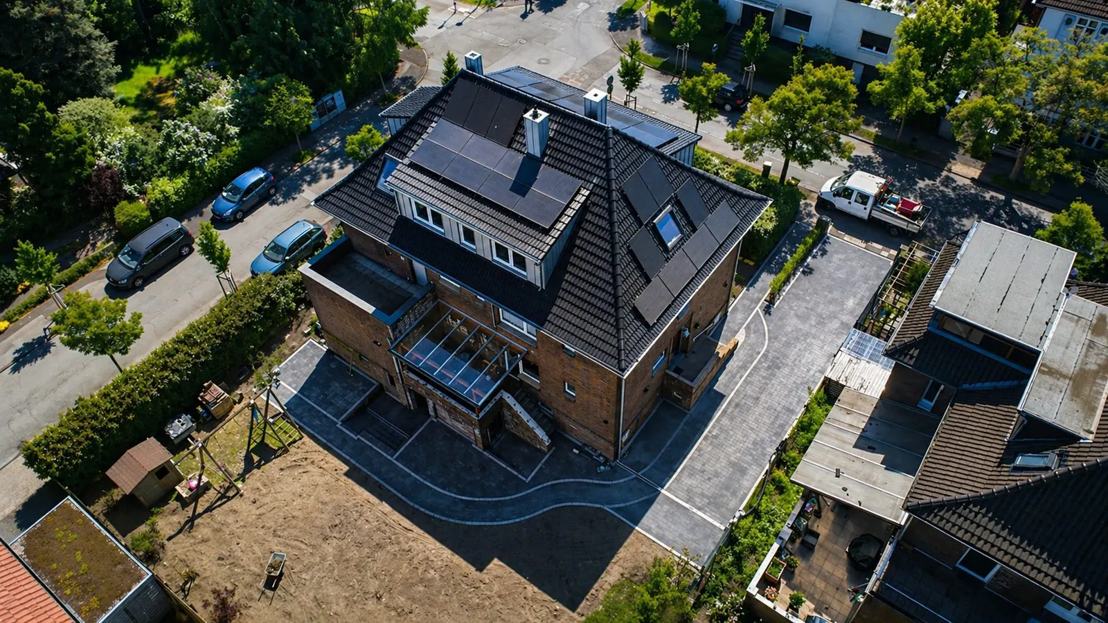 Luftaufnahme einer abgeschlossenen Außenanlage mit neu gepflasterter Hofeinfahrt, Garten und Zaun